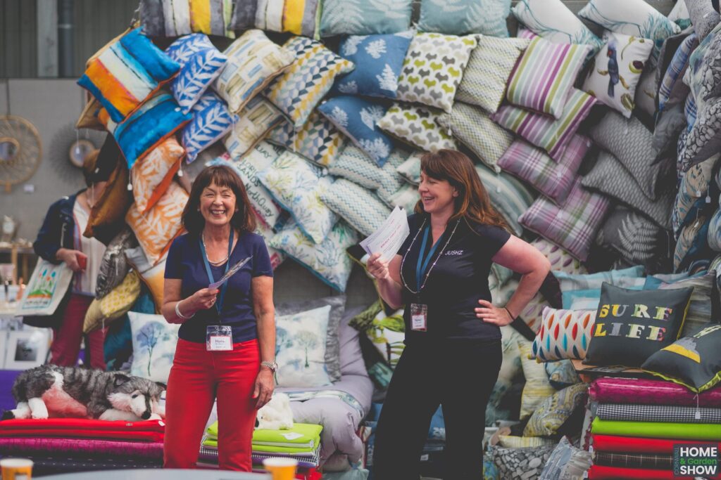 laughing women standing infront of wall of cushions